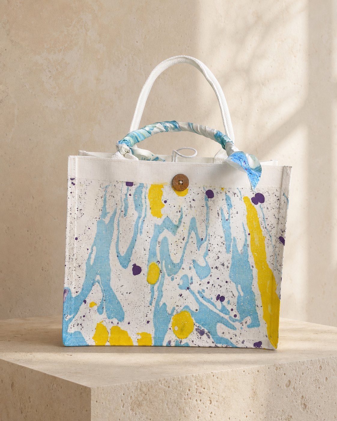 Sunlit Lagoon blue and yellow structured canvas tote on a warm stone plinth